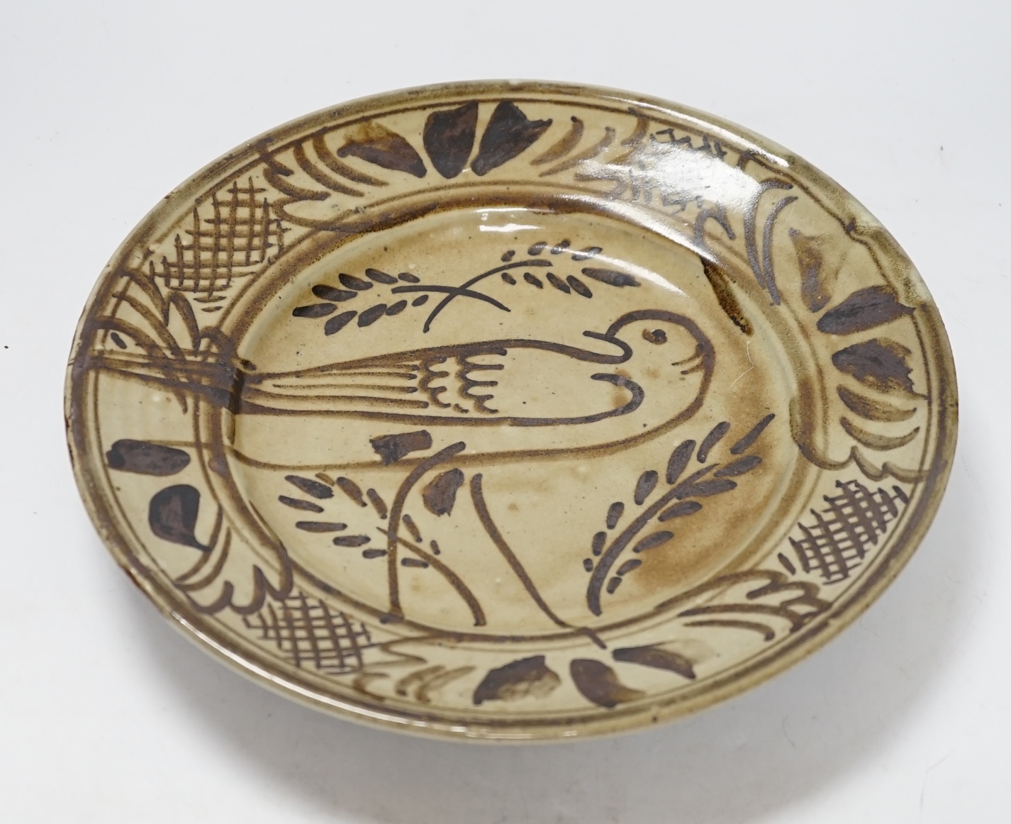 A Seth Cardew studio pottery stoneware dish, decorated with a bird and stylised flowers, 28cm in diameter
